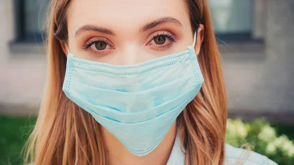 Крупним планом молода жінка в синій медичній масці дивиться на камеру — стокове фото