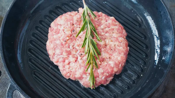 Vue grand angle de patty mince avec sel et branche de romarin sur poêle chaude — Photo de stock