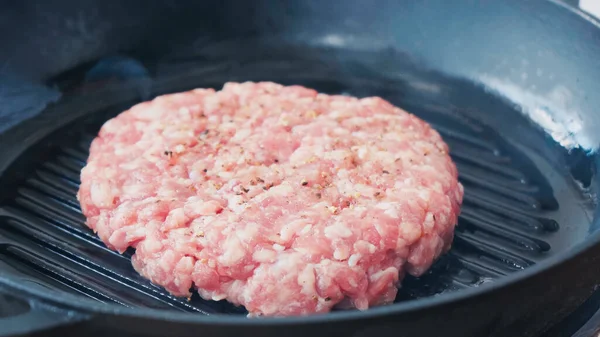 Nahaufnahme von Hackfleischpastete mit Salz und schwarzem Pfeffer in einer heißen Pfanne — Stockfoto