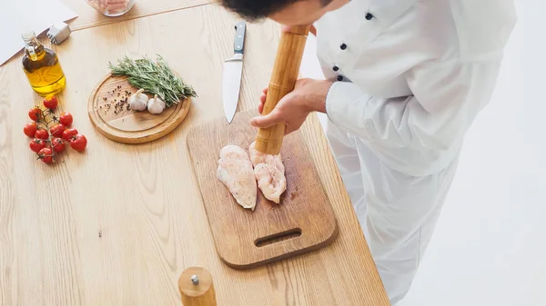 Blick aus der Vogelperspektive auf Koch würzt Hühnerfilet auf Schneidebrett — Stockfoto