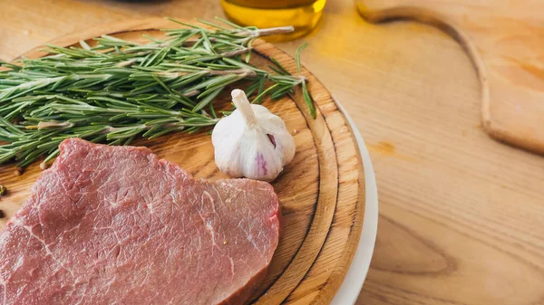 Vista de perto de bife de carne crua com ingredientes em tábua de corte de madeira — Fotografia de Stock