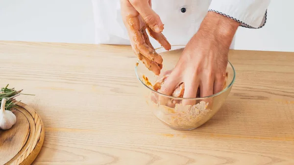 Cropped view of chef marinating sliced chicken in bowl on white background — Stock Photo