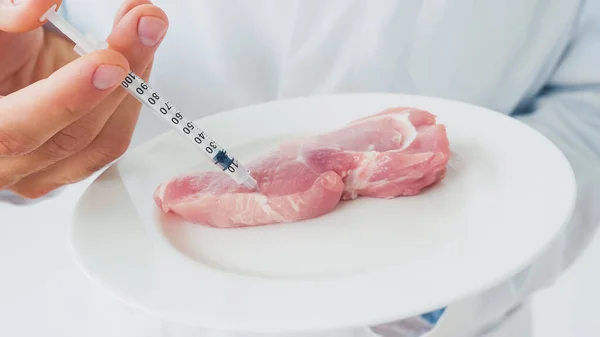 Cropped view of scientist injecting raw piece of beef on plate — Stock Photo