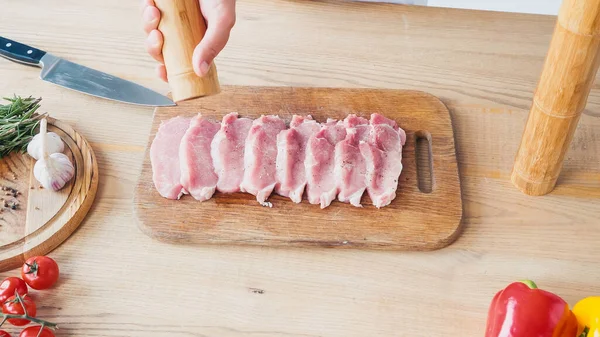 Visão parcial do homem com moinho de sal tempero pedaços de lombo de carne — Fotografia de Stock