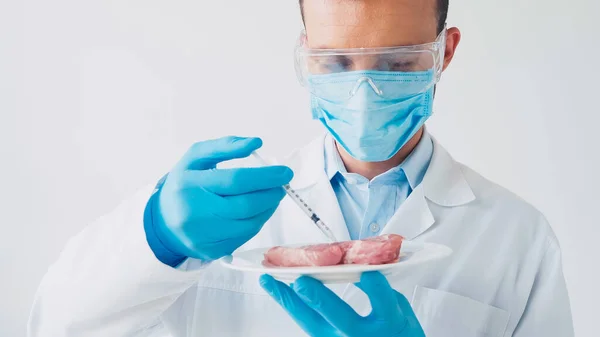 Scientist injecting syringe in piece of pork isolated on white — Stock Photo