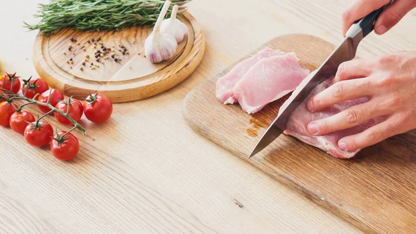 Partial view of man cutting beef tenderloin on chopping board on white — Stock Photo