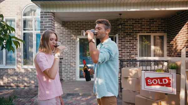 Man and woman drinking red wine near new house — Stock Photo