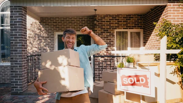 Homme excité tenant des boîtes et se réjouissant près de nouvelle maison — Photo de stock