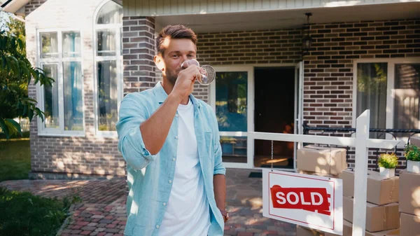 Homme tenant verre et boire du vin près d'une nouvelle maison — Photo de stock