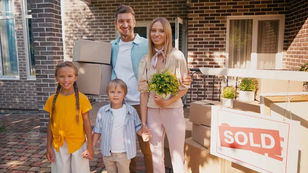 Familia feliz tomados de la mano y de pie cerca de casa nueva - foto de stock