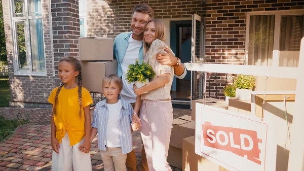 Joyful family holding hands and standing near new house — Stock Photo