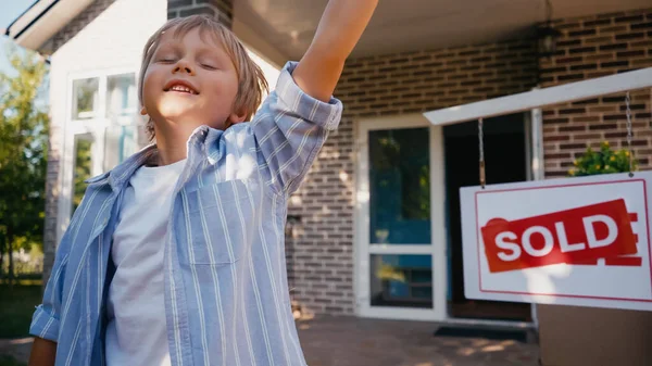 Glücklicher Junge mit geschlossenen Augen in der Nähe des neuen Hauses — Stockfoto