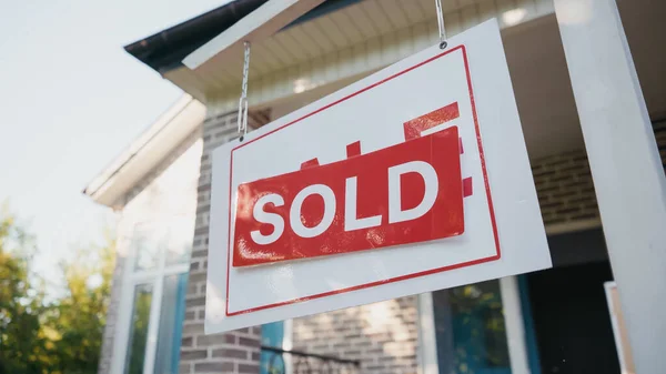 Klebriges Etikett mit verkauftem Schriftzug an Bord in der Nähe eines modernen Hauses — Stockfoto