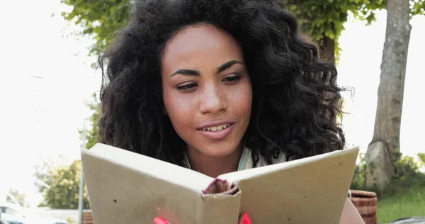 Mulher afro-americana feliz ler livro em capa dura — Fotografia de Stock