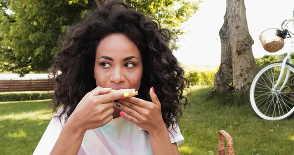 Encaracolado afro-americano mulher comendo pizza no parque — Fotografia de Stock