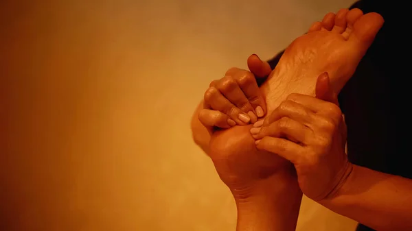 Vista ritagliata del massaggiatore massaggiante gamba di donna scalza sul tavolo da massaggio — Foto stock