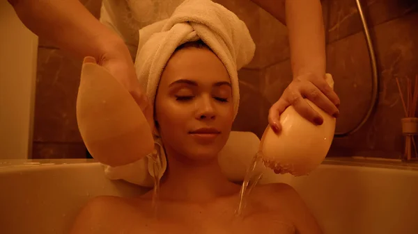 Thérapeute professionnel versant de l'eau de coquillages sur le jeune client dans la baignoire — Stock Photo