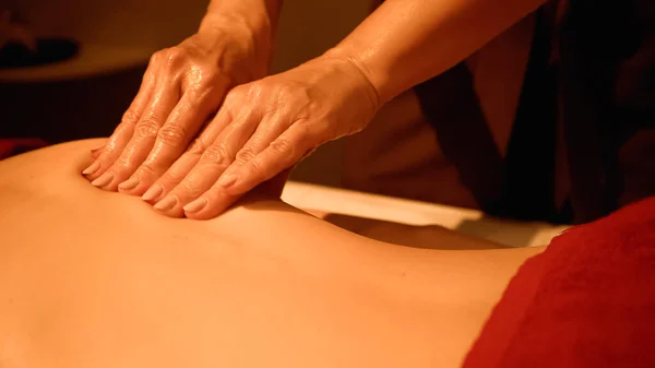 Vue partielle du masseur professionnel massant femme sur table de massage — Photo de stock