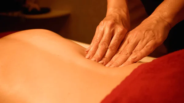 Vista cortada de massagista profissional massageando de volta da mulher na mesa de massagem — Fotografia de Stock