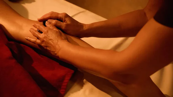 Vista recortada de masajista profesional haciendo masaje de piedra caliente a la mujer en el salón de spa - foto de stock