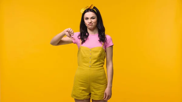 Жінка, що демонструє знак нелюбов, ізольована на жовтому — стокове фото