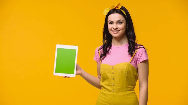 Улыбающаяся женщина держит цифровой планшет с зеленым экраном изолирован на желтый — стоковое фото