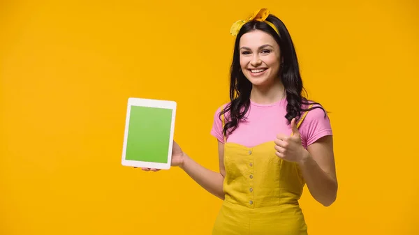 Позитивная женщина показывает, как во время проведения цифровой таблетки с хрома ключ изолирован на желтый — стоковое фото
