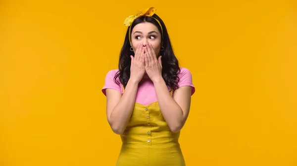 Excited woman covering mouth with hands isolated on yellow — Stock Photo