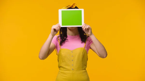 Mulher segurando tablet digital com tela verde isolada no amarelo — Fotografia de Stock