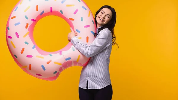 Gerente sonriente sosteniendo anillo de natación aislado en amarillo - foto de stock