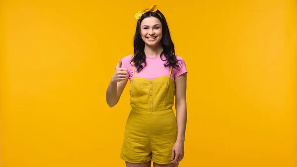 Молода усміхнена жінка показує, як ізольована на жовтому — стокове фото
