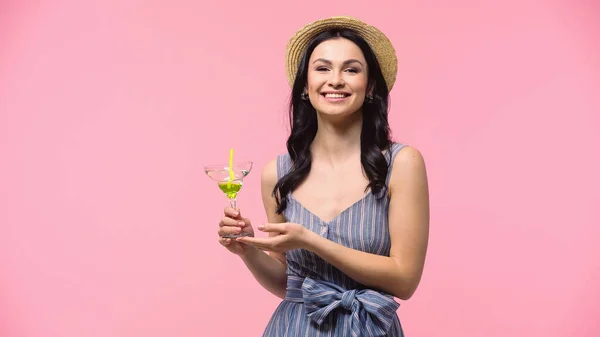 Mujer bonita en sombrero de paja celebración cóctel con paja aislada en rosa - foto de stock