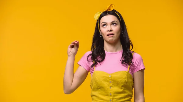 Skeptical woman gesturing and looking up isolated on yellow — Stock Photo