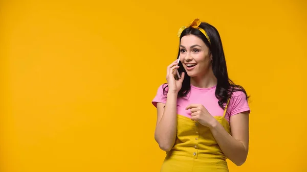 Mujer feliz en diadema hablando en smartphone aislado en amarillo - foto de stock