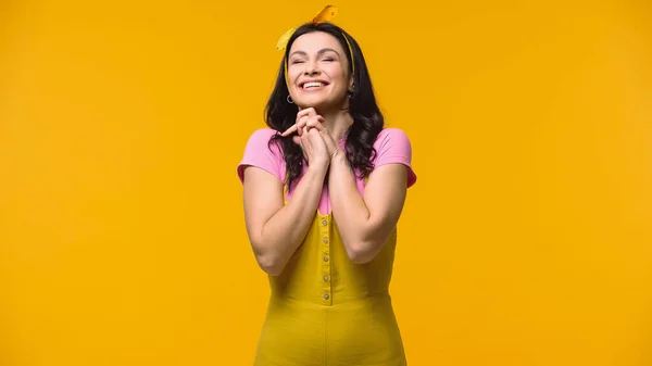 Zufriedene Frau steht mit geschlossenen Augen isoliert auf gelb — Stockfoto