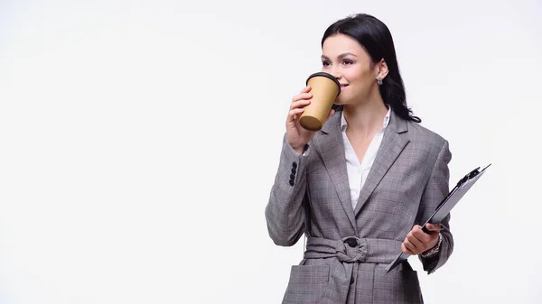 Mujer de negocios con chaqueta bebiendo café para ir y sujetando el portapapeles aislado en blanco - foto de stock