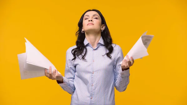 Exhausted businesswoman holding papers isolated on yellow — Stock Photo