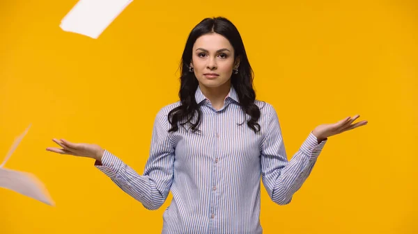 Businesswoman pointing with hands near papers in air isolated on yellow — Stock Photo