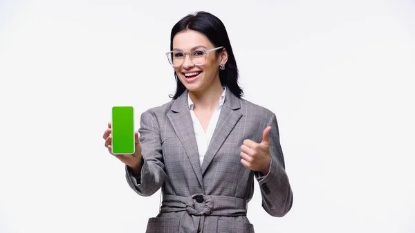 Улыбающаяся деловая женщина, держащая смартфон с пустым экраном и показывающая себя изолированной на белом — стоковое фото