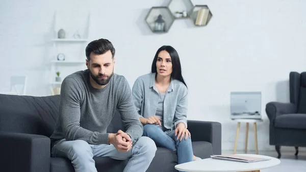 Mujer insatisfecha peleando con el hombre triste en la sala de estar - foto de stock