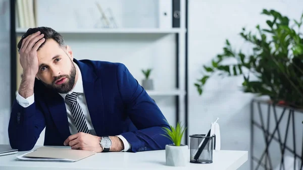 Frustrado hombre de negocios en traje sentado en la oficina - foto de stock