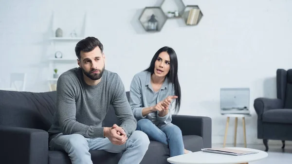Displeased woman quarreling with distracted man in living room — Stock Photo
