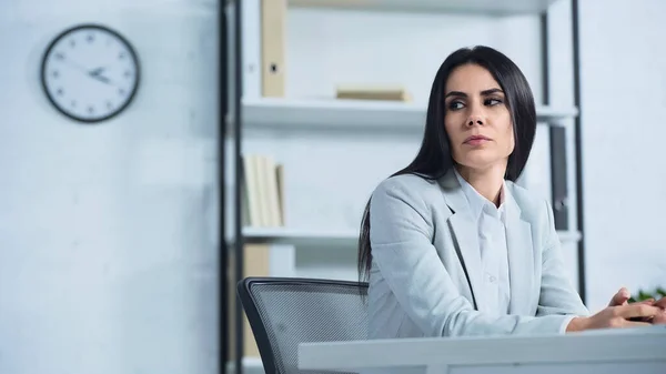 Mujer de negocios disgustada mirando hacia otro lado mientras se sienta en el escritorio - foto de stock