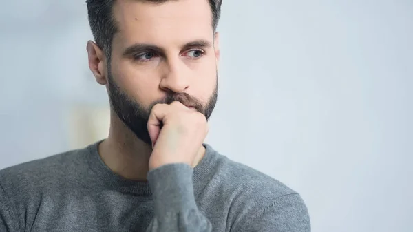 Hombre estresado y barbudo mirando hacia otro lado mientras piensa en casa - foto de stock
