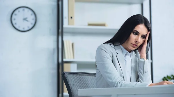 Upset businesswoman looking away while sitting at desk — Stock Photo