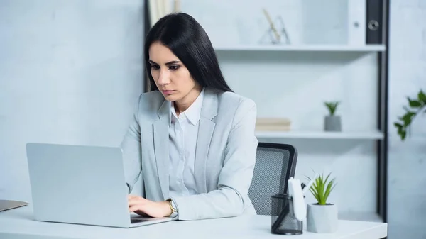 Brunette et inquiet femme d'affaires en utilisant un ordinateur portable dans le bureau — Photo de stock