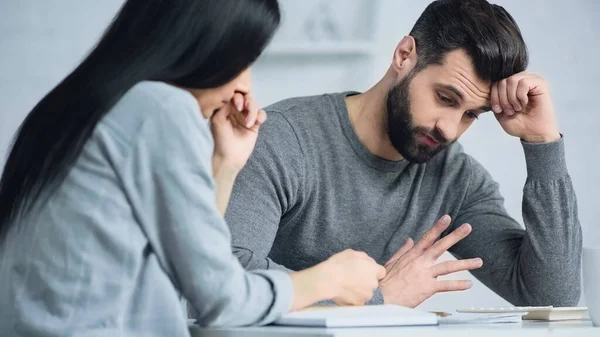 Mécontent homme regardant calculatrice près femme floue — Photo de stock