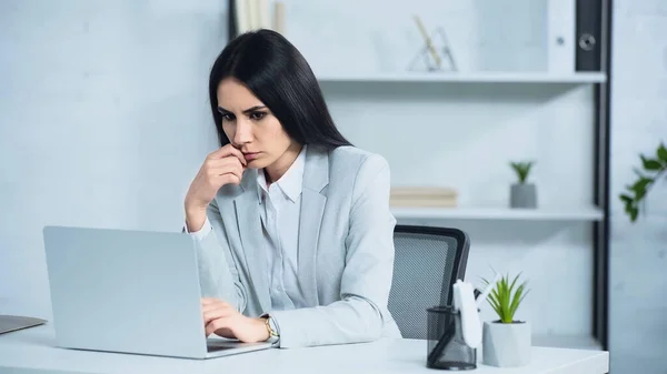 Mujer de negocios preocupada usando el ordenador portátil en la oficina - foto de stock