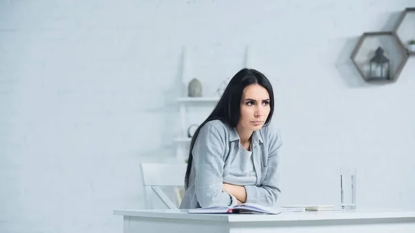 Беспокойная женщина смотрит в сторону, сидя за столом в офисе — стоковое фото