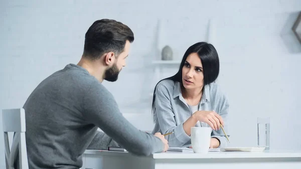 Mujer hablando con el hombre mientras discute la contabilidad y los impuestos en casa - foto de stock